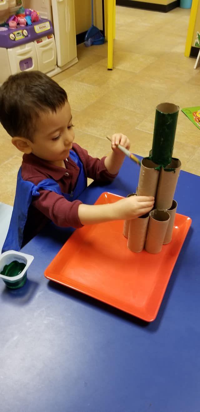 Boy coloring Christmas tree made of toilet paper rolls at Language Arts Academy Preschool In Spring TX Montessori